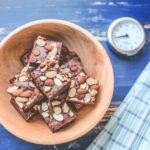 Wooden bowl with ingredients being mixed on a blue table, with a timer to indicate preparation time.