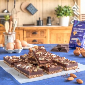 Homemade Chocolate Almond Protein Bars displayed on a blue table, surrounded by ingredients, ready to be enjoyed.